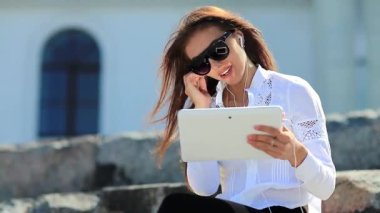 İş kadını tablet bilgisayarla konuşuyor. Beyaz tablet bilgisayarlı gözlüklü çekici bir kadın görüntülü sohbet yoluyla iletişim kuruyor.