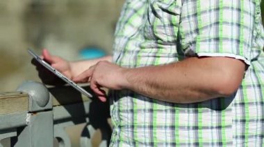 İşadamı tablet bilgisayarla çalışıyor, kapatın. Adam tablet bilgisayar kullanıyor, tabletini elinde tutuyor.