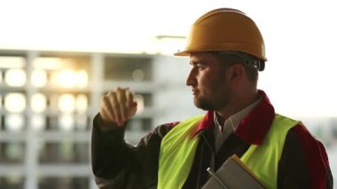 İnşaat alanındaki inşaat belgeleriyle birlikte inşaat ustası ileriye bakıyor. Proje alanında inşaat belgelerine sahip bir inşaatçı