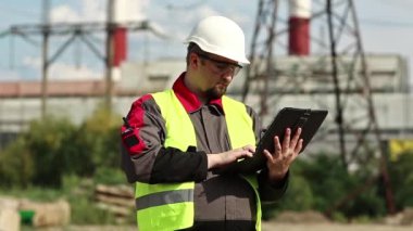 Elektrik santralinde kişisel bilgisayarı olan bir mühendis. Isı elektrik santralinde bilgisayar mühendisi. Isı elektrik santralinde kasklı işçi, mühendislik denetimi.