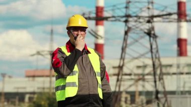 Elektrik santralinde taşınabilir radyo vericisi olan güçlü bir adam. Isı santrali enerji mühendisliği uzmanı radyo istasyonu aracılığıyla iletişim kuruyor.