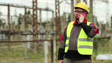 Elektrik santralindeki işçiler akıllı telefondan konuşur. Elektrik santralinde cep telefonu ve taşınabilir radyo vericisi konusunda uzman.