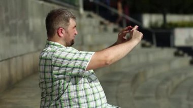 Şişman adam akıllı telefondan video kaydediyor. Adam cep telefonuyla fotoğraf çekiyor.