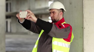 İnşaatçı akıllı telefondan video kaydediyor. İnşaat alanında çalışan biri cep telefonuyla fotoğraf çekiyor.