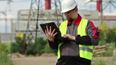 Elektrik santralinde kişisel bilgisayarda çalışan bir elektrik mühendisi. Isı elektrik santralinde çalışan, mühendislik denetimi altında çalışan bir işçi. Tablet bilgisayarlı fabrika işçisi