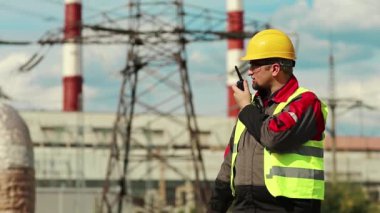 Elektrik santralinde taşınabilir radyo vericisi olan güçlü bir adam. Isı santrali enerji mühendisliği uzmanı radyo istasyonu aracılığıyla iletişim kuruyor.