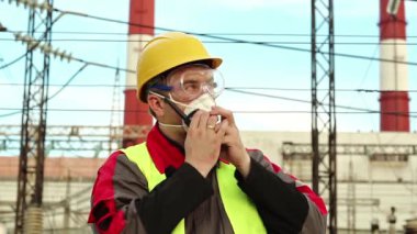 Solunum cihazı işçisi elektrik santralindeki taşınabilir radyo vericisiyle konuşuyor. Gaz maskesi, gözlükler ve ısı santralinin başlığı konusunda uzman olan elektrik mühendisi radyo istasyonu aracılığıyla iletişim kuruyor.