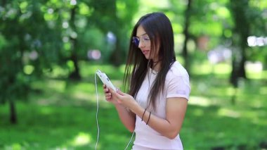 Gözlüklü güzel kadın halka açık alanda cep telefonu kullanıyor. Büyük gözlüklü güzel bir kadın akıllı telefonunu elinde tutuyor. Çekici kız şehir parkında akıllı telefon kullanıyor.