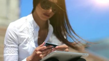 Tablet bilgisayarda kredi kartıyla alışveriş yapmak. Tablet bilgisayar kullanan bir iş kadını kredi kartıyla online alışveriş yapıyor. Güzel kız elinde beyaz tablet ve mavi kredi kartı tutuyor.