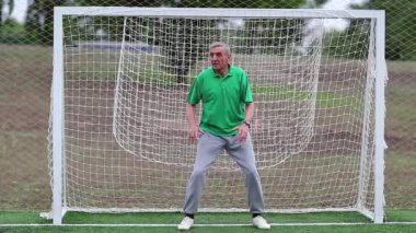 Yeşil tişörtlü kaleci futbol sahasındaki kapıyı koruyor. Son sınıf öğrencisi futbol kalesinde duruyor. Futbol kapısında aktif yaşlı bir atlet. Fiziksel aktivite kalori yakmaya yardımcı olur.