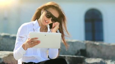 İş kadını tablet bilgisayarla iletişim kuruyor. Beyaz tabletli gözlüklü çekici bir kadın Skype üzerinden iletişim kuruyor, neşeli bir ruh hali içinde.