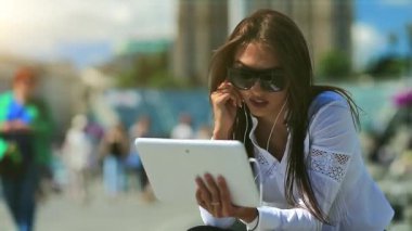 İş kadını çeşmelerin yanında oturur ve tablet bilgisayarla iletişim kurar. Beyaz tabletli gözlüklü çekici bir kadın Skype üzerinden iletişim kuruyor, neşeli bir ruh hali içinde.