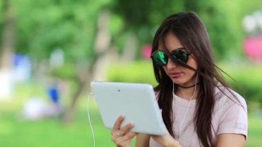 Çekici kız tablet bilgisayardaki fotoğraflara bakıyor. Güzel bir kadın onun tablet bilgisayarında çalışıyor.