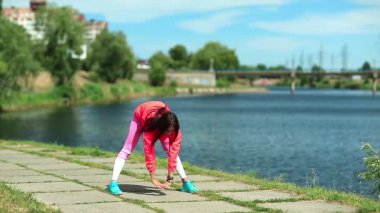 Sporcu kadın fiziksel egzersiz yapıyor ve olay yerinde koşuyor. Aktif genç bir kadın göl kenarında egzersiz yapıyor. Kız spora gidiyor, kız spor yapıyor. Fiziksel aktivite kalori yakmaya yardımcı olur.