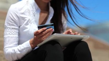 Tablet bilgisayarda kredi kartıyla alışveriş yapmak. Tablet bilgisayar kullanan bir iş kadını kredi kartıyla online alışveriş yapıyor. Güzel kız elinde beyaz tablet ve mavi kredi kartı tutuyor.