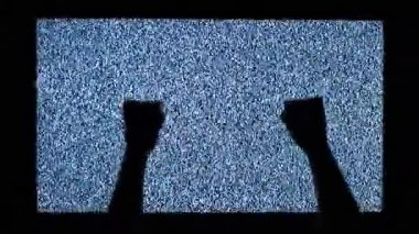TV kanalı gürültüsü ve televizyon ekranında ellerin siyah silueti. Televizyon ekranında eller vuruyor