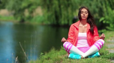 Kız göl kenarında meditasyon yapıyor. Spor kıyafetli kadın göletin kenarında oturup meditasyon yapıyor. Meditasyon - bireyin zihni çalıştırdığı, eğittiği ya da bir bilinç biçimini tetiklediği uygulama