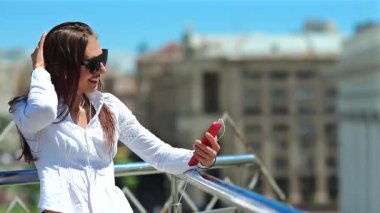 Kız akıllı telefondan konuşuyor. Akıllı telefonu olan kadın video kaset aracılığıyla iletişim kuruyor. Şehirde kırmızı cep telefonu olan çekici bir kız.