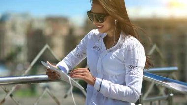 Güneş gözlüklü genç çekici kız tablet bilgisayar kullanıyor. Kız elinde tablet bilgisayarla