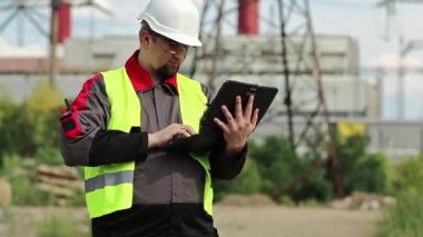 Elektrik santralinde kişisel bilgisayarda çalışan bir elektrik mühendisi. Isı elektrik santralinde çalışan, mühendislik denetimi altında çalışan bir işçi. Tablet bilgisayarlı fabrika işçisi