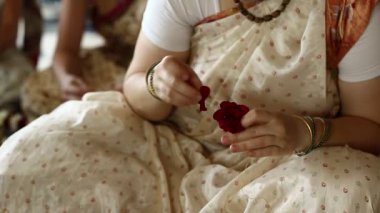 UKRAINE, KIEV, 4 AĞUSTOS 2017: Hindu geleneksel renkli kostümlü kadınlar Krishna tapınağında çiçek çelengi yapıyorlar, Krishna tanrısına hizmet ediyorlar
