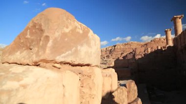 Petra 'daki Büyük Tapınak ya da Kanatlı Aslanlar Tapınağı' nın antik sütunları - Ürdün Haşim Krallığı 'nın tarihi ve arkeolojik kaya kesimi şehri. Arka planda dağlara oyulmuş kraliyet mezarları.