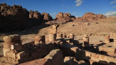 Petra 'daki Büyük Tapınak ya da Kanatlı Aslanlar Tapınağı' nın antik sütunları - Ürdün Haşim Krallığı 'nın tarihi ve arkeolojik kaya kesimi şehri. Arka planda dağlara oyulmuş kraliyet mezarları.