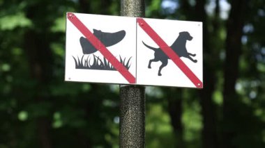 Şehir parkında plaka var. Çimlerde yürümek yasak ve köpeklere izin yok. Köpek yasağı tabelası