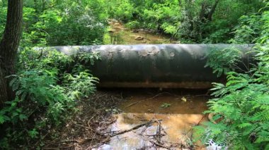 Eski ana boru hattı, eski lastikler ve diğer çöpler küçük bir nehrin kıyısında, çevreyi suistimal ediyor.
