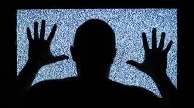TV kanalı gürültüsü ve televizyon ekranının yanındaki siyah siluet. Adam televizyon ekranında grev yapıyor