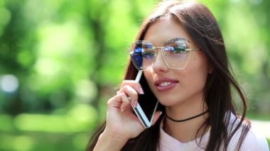 Akıllı telefonlu bir iş kadını, yakın plan. Gözlüklü güzel kadın cep telefonuyla konuşuyor. Kız cep telefonuyla konuşuyor. Beyaz akıllı telefonlu bir kadın.