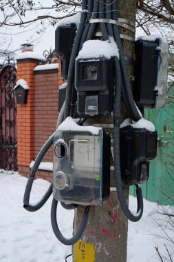 Özel evlerdeki ev tüketicileri için elektrik sayaçları bir direğe asılı.