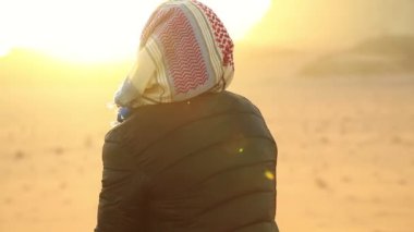 Türbanlı kadın, Ürdün 'ün Haşarat Krallığı' ndaki Wadi Rum çölünde güneşe bakıyor. Gün batımında Wadi Rum çölünün güzel manzarası. Ürdün 'deki Wadi Rum Çölü' nün muhteşem manzarası, aynı zamanda Ay Vadisi olarak da bilinir.