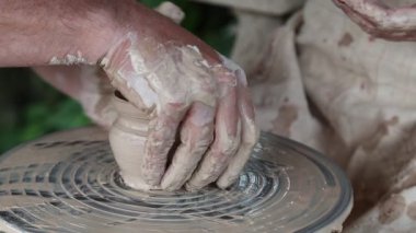 Bir çömlekçinin elleri ve çırağı. Kadın ve erkek çömlek çarkında demlik yapıyorlar. Kadın çömlekçinin öğrencisidir. Erkek ve kadın elleri