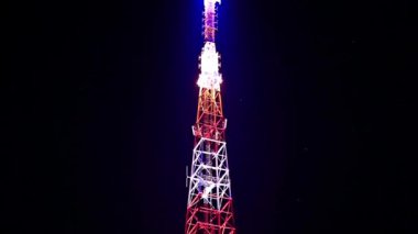 Geceleri telekomünikasyon kulesi. Cep telefonu iletişimi, televizyon, internet, radyo antenleri. İletişim kulesi anteninde siyah arkaplan üzerine aydınlatma