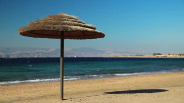 Ürdün 'ün Haşim Krallığı, Tala Körfezi' ndeki tropik tatil beldesi. Kızıl Deniz, Akabe Körfezi. Güzel sahildeki şemsiye. Diğer kıyıdaki İsrail ve Mısır 'a bak.