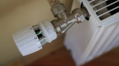 Adam akünün sıcaklığını ayarlıyor. Isı kontrollü merkezi ısıtıcı. Sıcaklık regülatörlü ısıtma pili, ev ısıtma sistemi