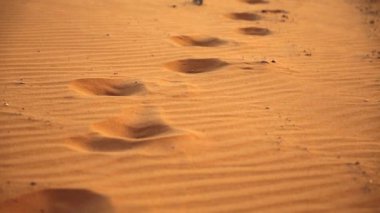 Ürdün 'ün Haşim Krallığı' ndaki Ay Vadisi olarak da bilinen Wadi Rum çölündeki sarı kumdaki ayak izleri. Wadi geleneksel olarak vadiden bahseden bir terimdir.