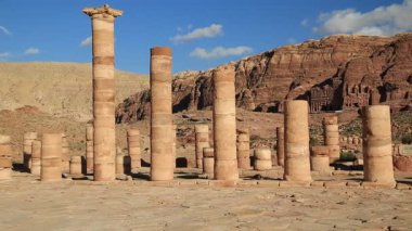 Petra 'daki Büyük Tapınak Sütunları - Ürdün Haşim Krallığı' ndaki antik tarihi ve arkeolojik kaya kesimli şehir. Arka planda dağlara oyulmuş kraliyet mezarları. UNESCO dünya mirası sahası