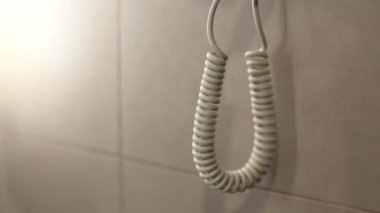 Banyoda saç kurutma makinesi var. Banyonun içindeki duvarda beyaz saç kurutma makinesi var.