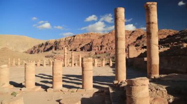 Petra 'daki Büyük Tapınak ya da Kanatlı Aslanlar Tapınağı' nın antik sütunları - Ürdün Haşim Krallığı 'nın tarihi ve arkeolojik kaya kesimi şehri. Arka planda dağlara oyulmuş kraliyet mezarları.