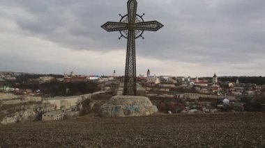 Ukrayna 'nın batısındaki Kamianets-Podilskyi şehrinde büyük metal haç. Arka planda - Podolia 'nın tarihi bölgesinde yer alan Kamianets-Podilskyi eski kenti