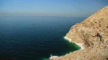 Yeşil su ve beyaz tuz birikintileri sarı kayalarda. Ürdün 'ün Haşim Krallığı' nda Ölü Deniz 'in Rocky sahili