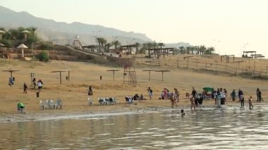 JORDAN, ÖLÜ SEA, 8 ARALIK 2016: Ürdün 'deki Ölü Deniz plajında insanlar. İnsanlar Ölü Deniz 'in tuzlu sularında yüzüyor ve rahatlıyor. Ürdün Haşimi Krallığı.