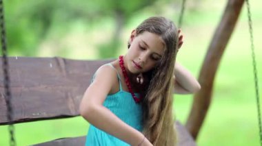 Mavi elbiseli çekici kız bankta oturur ve uzun saçlarını tarar. Güzel kız onun uzun saçlarını tarıyor. Saç fırçalı kız bahçede bankta oturuyor.