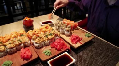 Adam restoranda masada oturur ve Japon yemeği yer. Adam Japon restoranında suşi yiyor.