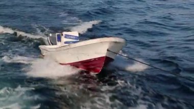 Yolcuları olmayan küçük bir tekne büyük bir motorun arkasına bağlı.