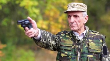 Siyah silahlı bir adam. Askeri üniformalı kıdemli bir adam tabancayla ateş ediyor. Poligondaki emekli memur. Askeri üniformalı kıdemli bir adam ormanda tabanca ateşliyor.