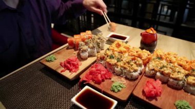 Adam restoranda masada oturur ve Japon yemeği yer. Adam Japon restoranında suşi yiyor.