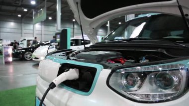 Ukrayna, Kiev, 10 Haziran 2016: İnsanlar elektrikli otomobil fuarında. Beyaz Kia Soul Ev electromobile ücret uygulanır. Araba ile openned kaporta